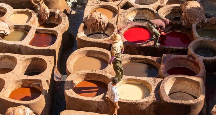 Gros plan sur des ouvriers manipulant des peaux de cuir dans des cuves aux couleurs vives à la tannerie de Fès.