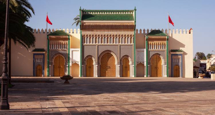 Portail cérémoniel grandiose du Palais Royal de Meknès orné de carreaux verts et de drapeaux marocains.