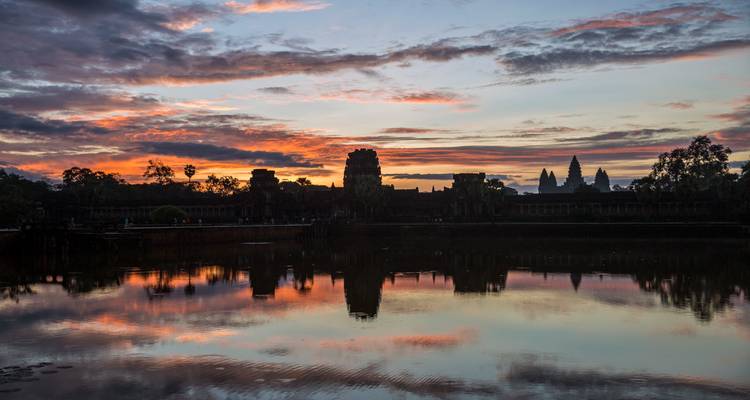 Dramatic sunset colours reflect on the moat in front of Angkor Wat’s dark silhouette.