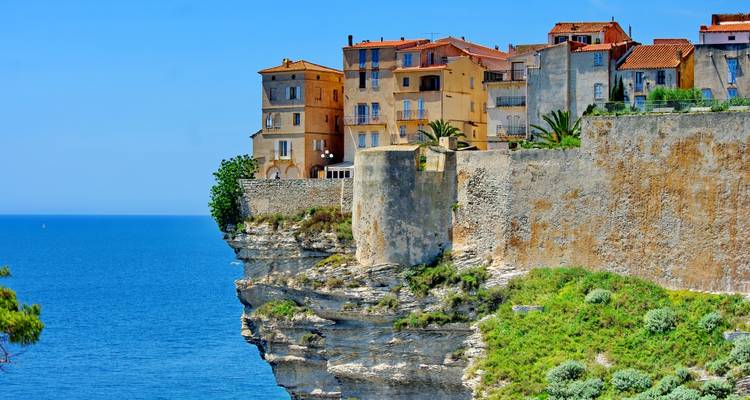 Dramatic cliff-top town of Bonifacio with pastel houses perched above the bright blue Mediterranean Sea.