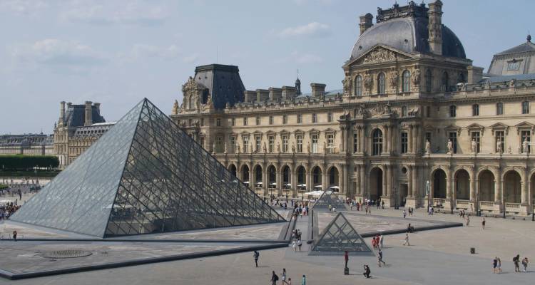 Iconic glass pyramid of the Louvre Museum stands before the historic palace buildings
