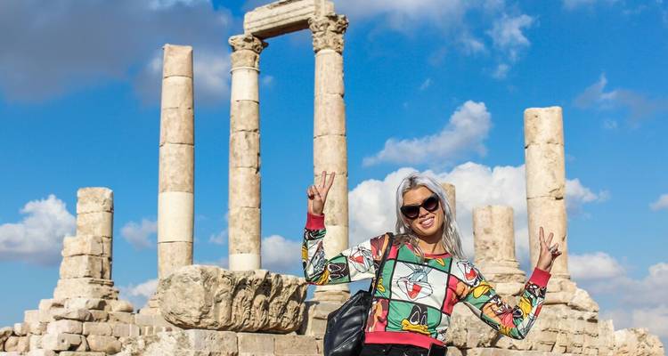 Visitor flashes peace sign in front of the ancient columns of the Amman Citadel.