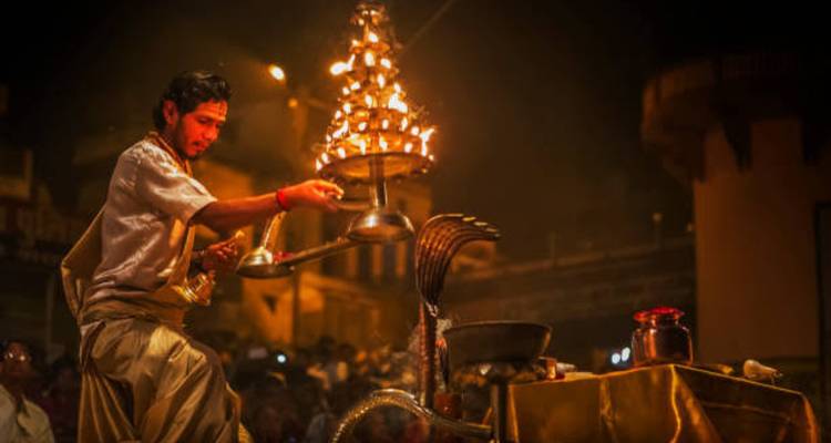 Un sacerdote balancea una lámpara multipisos ardiente durante un Aarti vespertino dramático en los ghats.