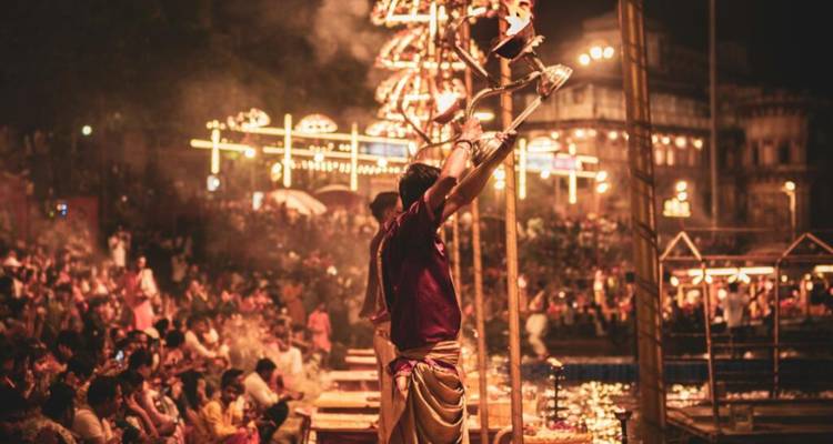 Las multitudes observan a los sacerdotes elevar lámparas encendidas durante una ceremonia nocturna vibrante en el Ganges.
