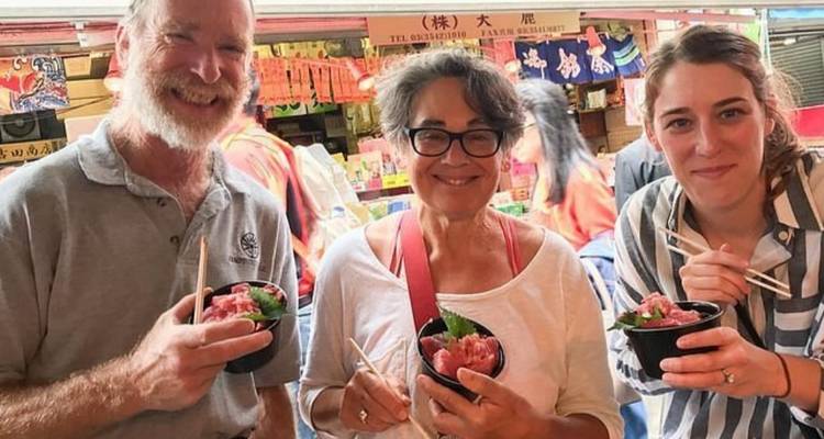 Reisende, die frische Speiseschalen an einem belebten japanischen Marktstand probieren.