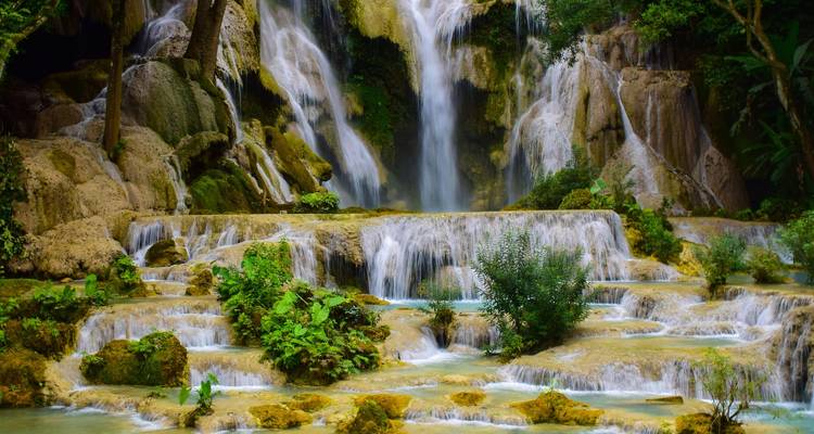 Meervoudige tropische waterval die over kalkstenen terrassen naar beneden stroomt, omgeven door groen