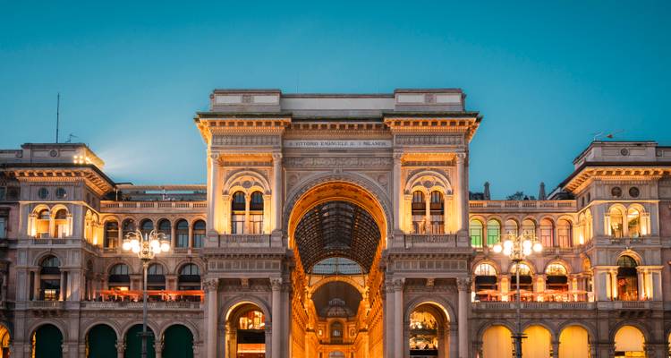 Evening lights glow on the grand arch of Galleria Vittorio Emanuele II facing Piazza del Duomo in Milan.