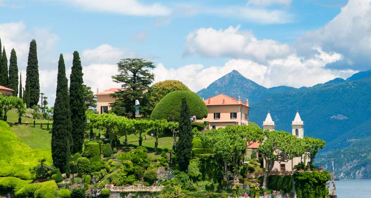 Lush terraced gardens and elegant villas line the shore of Lake Como with alpine peaks in the background.