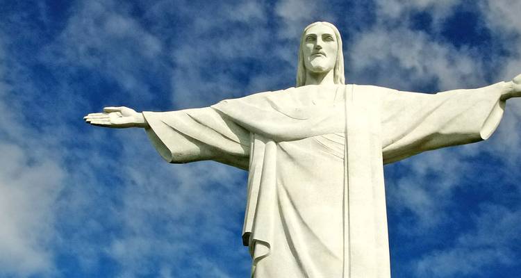 Iconic white Christ the Redeemer statue with outstretched arms set against a vivid blue sky.