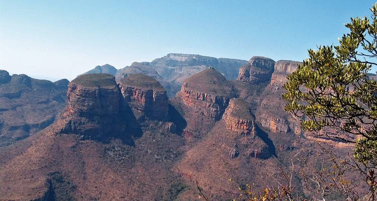 Rugged red cliffs and mesa formations rising from Blyde River Canyon under a clear sky.