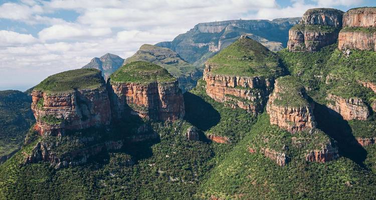Verdant cliffs of the Three Rondavels glowing with contrasting red rock layers and green vegetation.