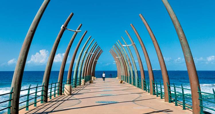 Futuristic whalebone pier in Umhlanga stretching out over the Indian Ocean with two walkers.