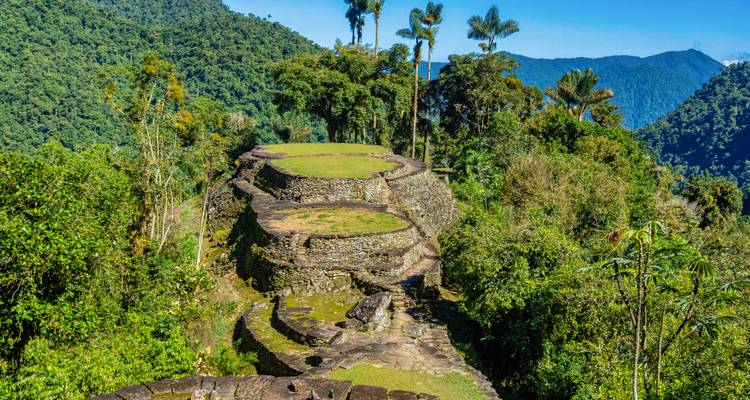 Stone terraces of the ancient Ciudad Perdida archaeological site rise amid lush jungle and mountain scenery.