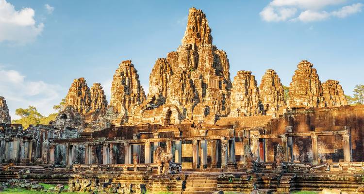 Majestic face towers and sandstone ruins of Bayon Temple at Angkor Thom glowing in warm light