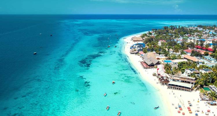 Aerial view of turquoise waters and white sandy coast with boats and villages in Zanzibar.