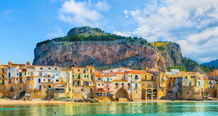 Colorful seaside town of Cefalù backed by a dramatic cliff and clear turquoise water