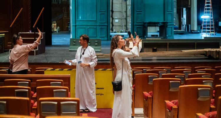 Bezoekers maken foto's op het podium van het Royal Opera House Muscat tijdens een rondleiding achter de schermen.