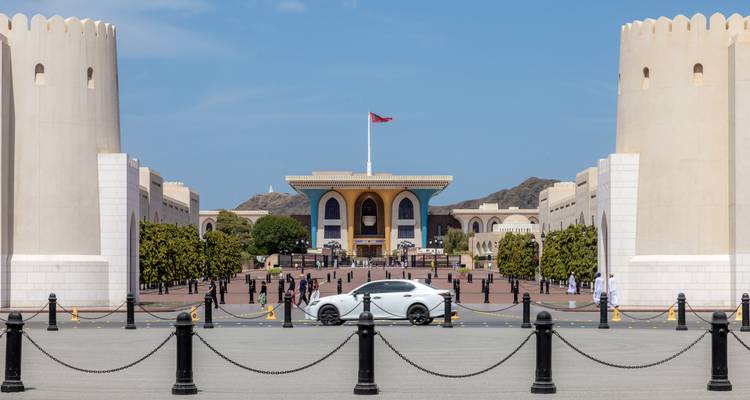 Uitzicht op het Al Alam Palace omgeven door versterkte witte torens met een Omaanse vlag die hoog wappert.