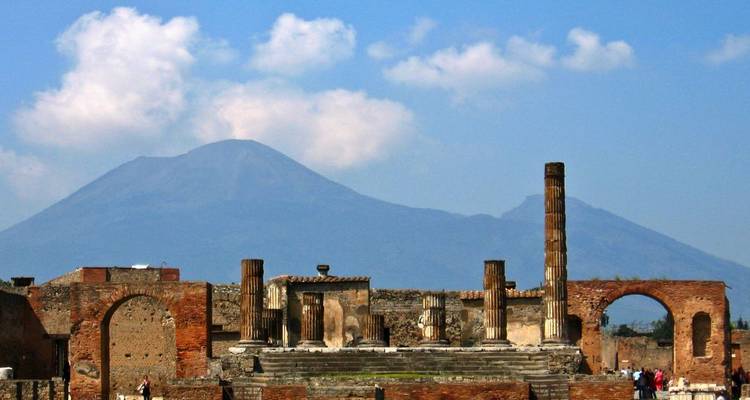 Uitzicht op de oude zuilen van Pompeii met de Vesuvius op de achtergrond onder een heldere hemel.
