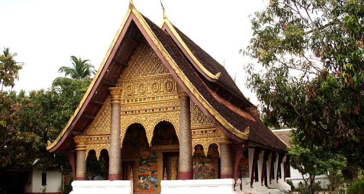 De rijkelijk versierde gevel van Wat Xieng Thong met meerdere daklagen en ingewikkelde gouden stencilwerk.