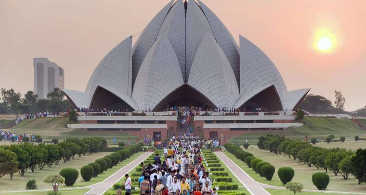 Der Lotus-Tempel in Delhi, umrahmt von Gärten bei Sonnenuntergang, mit Menschenmengen, die entlang des Weges spazieren.