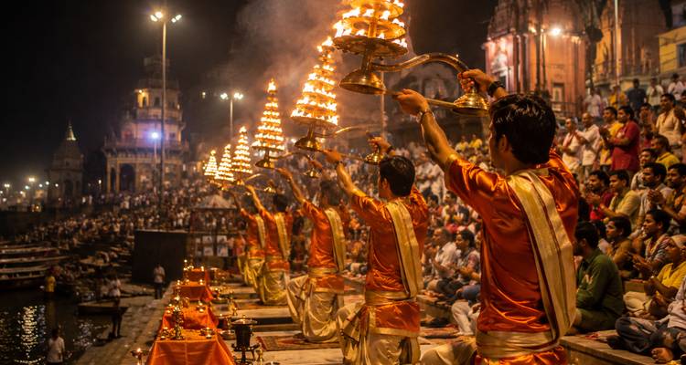 Abendliche Ganga Aarti in Varanasi mit Priestern, die brennende Lampen vor einer großen versammelten Menschenmenge halten.