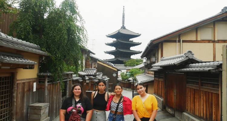 Group of travellers posing on a narrow Kyoto lane with Yasaka Pagoda rising behind.