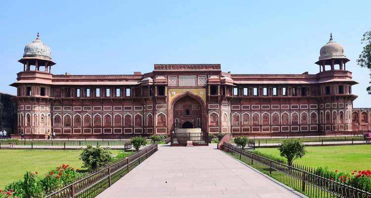 Long symmetrical view of a red-sandstone palace wing and garden path at Agra Fort.