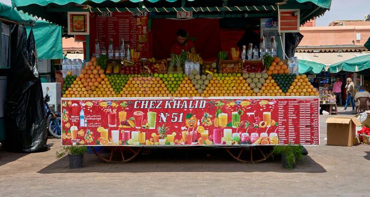 Stand de jus frais empilé haut de fruits colorés au marché de Jemaa el-Fna.