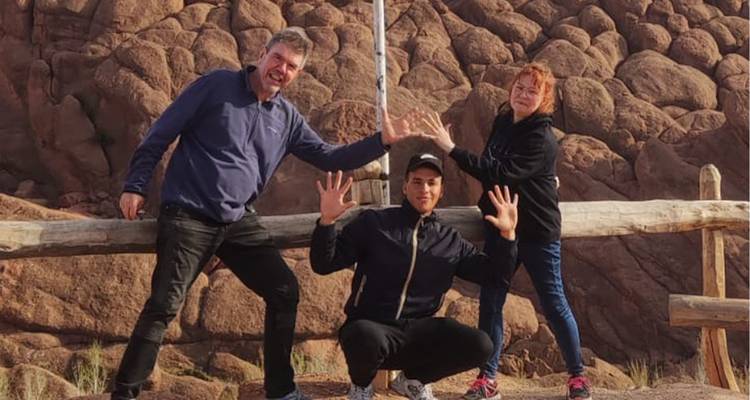Trois voyageurs posant de manière ludique devant des formations rocheuses arrondies de couleur rougeâtre