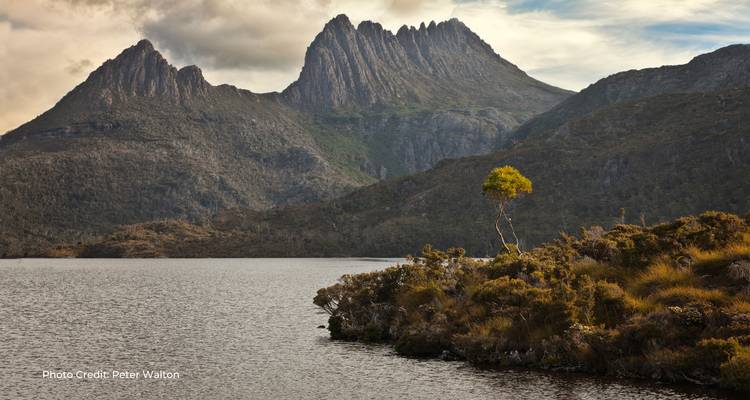 La crête de la Cradle Mountain s'élevant au-dessus d'un lac tranquille sous un ciel nuageux et dramatique