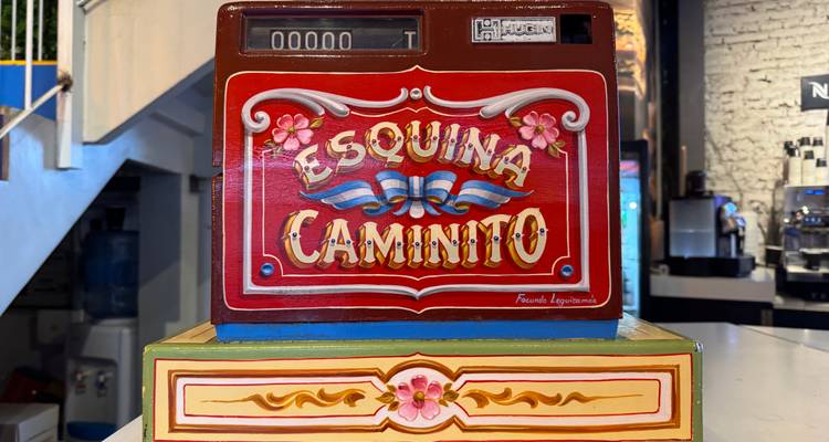Decoratief geldkistje beschilderd met de woorden 'Esquina Caminito' in traditionele fileteado-stijl.