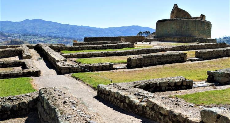 Sunlit ruins of Ingapirca temple complex with terraced stone foundations and distant Andes.