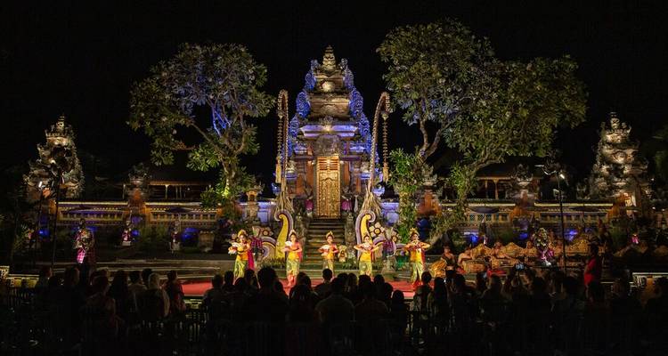 Night-time Balinese dance performance on an illuminated temple stage before an audience.