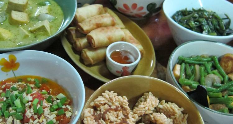 Assortiment van Thaise gerechten met onder meer loempia's, curry en groenten op tafel.