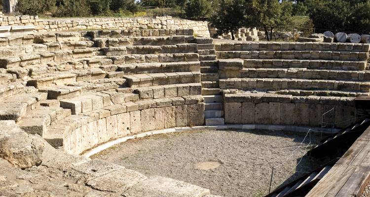 Ancient stone amphitheatre with semicircular seating carved into the hillside.