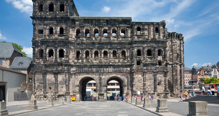 Ancient Porta Nigra gate in Trier with tourists exploring the historic Roman ruins.