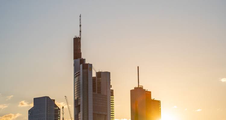 Moderne Frankfurtse wolkenkrabbers die glanzen in een gouden zonsondergang met de zon die achter de skyline verdwijnt.