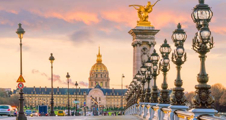Les candélabres ornés du Pont Alexandre III menant au dôme des Invalides sous un ciel de coucher de soleil coloré