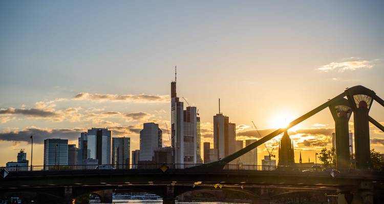 Silhouette de l'horizon urbain moderne de Francfort au coucher du soleil derrière un pont enjambant le Main.