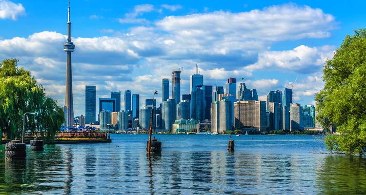 Panoramisch uitzicht op de skyline van Toronto met de CN Tower, gezien over het water op een zonnige dag.