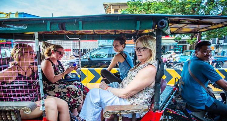 Groupe de voyageurs se déplaçant à bord d'un tuk-tuk motorisé coloré dans les rues animées de la ville.