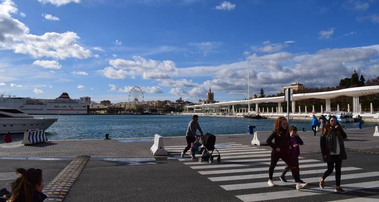 Families crossing a harbour plaza with cruise ship and modern promenade in the background at Malaga port.