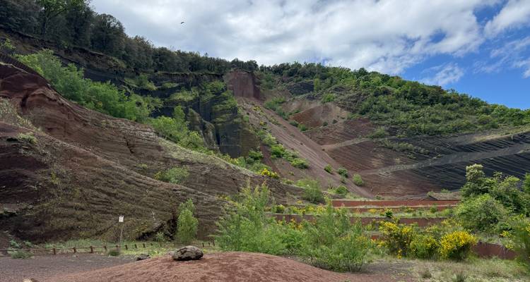 Des couches colorées de roche volcanique rouge et de végétation verte à l'intérieur d'un cratère éteint.