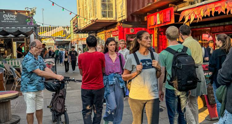 Drukke steeg van een Kopenhagense street-food markt vol kleurrijke eetgelegenheden in zeecontainers.