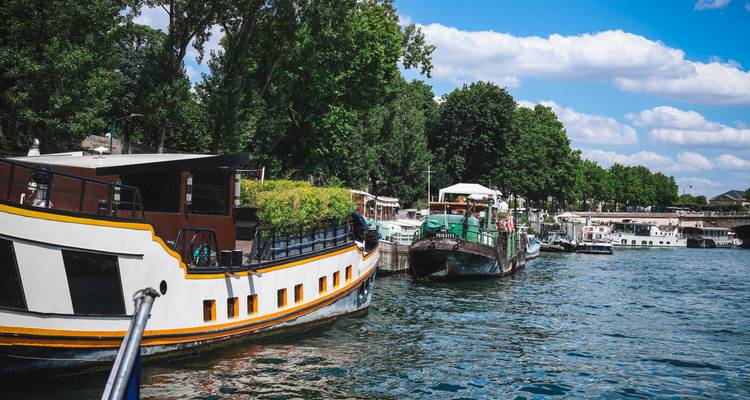Gros plan de péniches colorées naviguant sur les eaux bleues de la Seine par une journée ensoleillée.