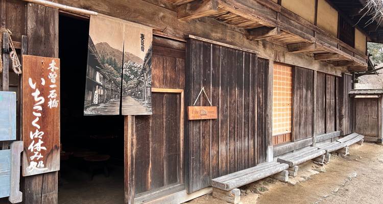 Verouderd houten gebouw in poststijl met Japanse borden en bankjes buiten.