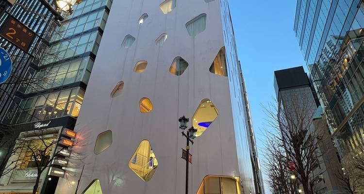 Slanke moderne witte gebouw met onregelmatige raamvormen in een stedelijke canyon.