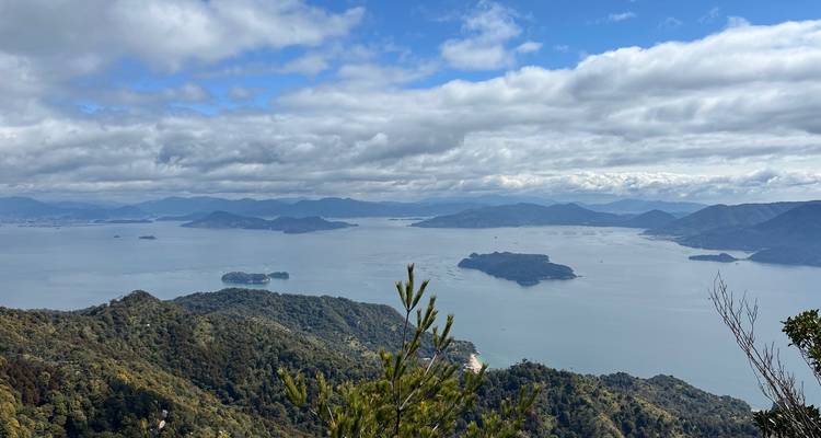 Panoramisch uitzicht over de Seto Binnenzee met meerdere groene eilanden en verre bergen.