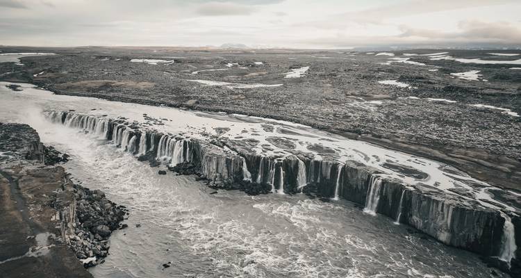 Cascade du Selfoss se déversant largement sur de nombreuses cornices rocheuses dans un paysage aride.